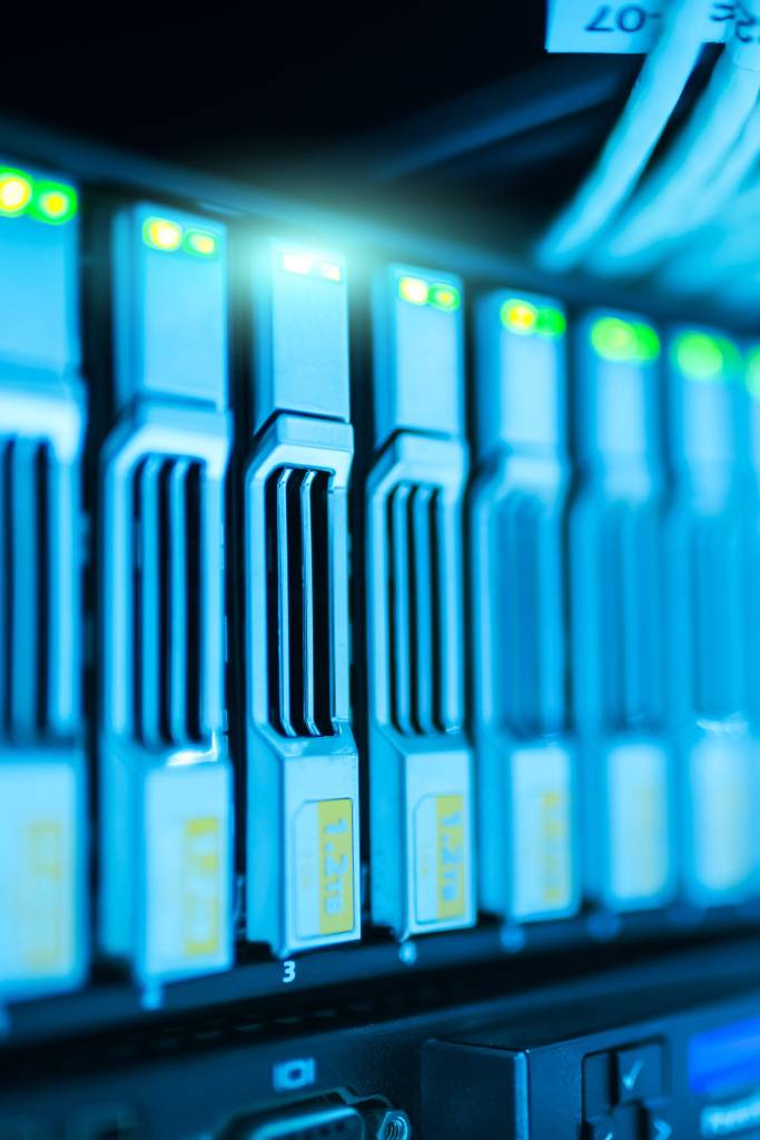 Server hard drives with glowing indicator lights in a data storage rack.